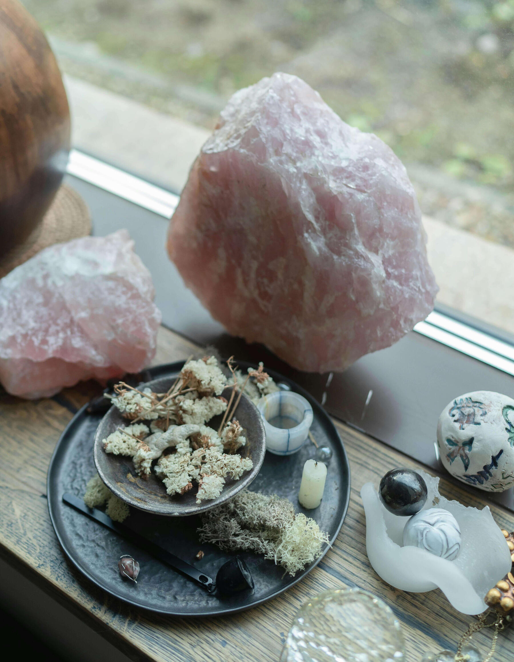 Rose Quartz Crystal Photo of large rose quartz crystals and smaller crystals, candles and bowls of moss.