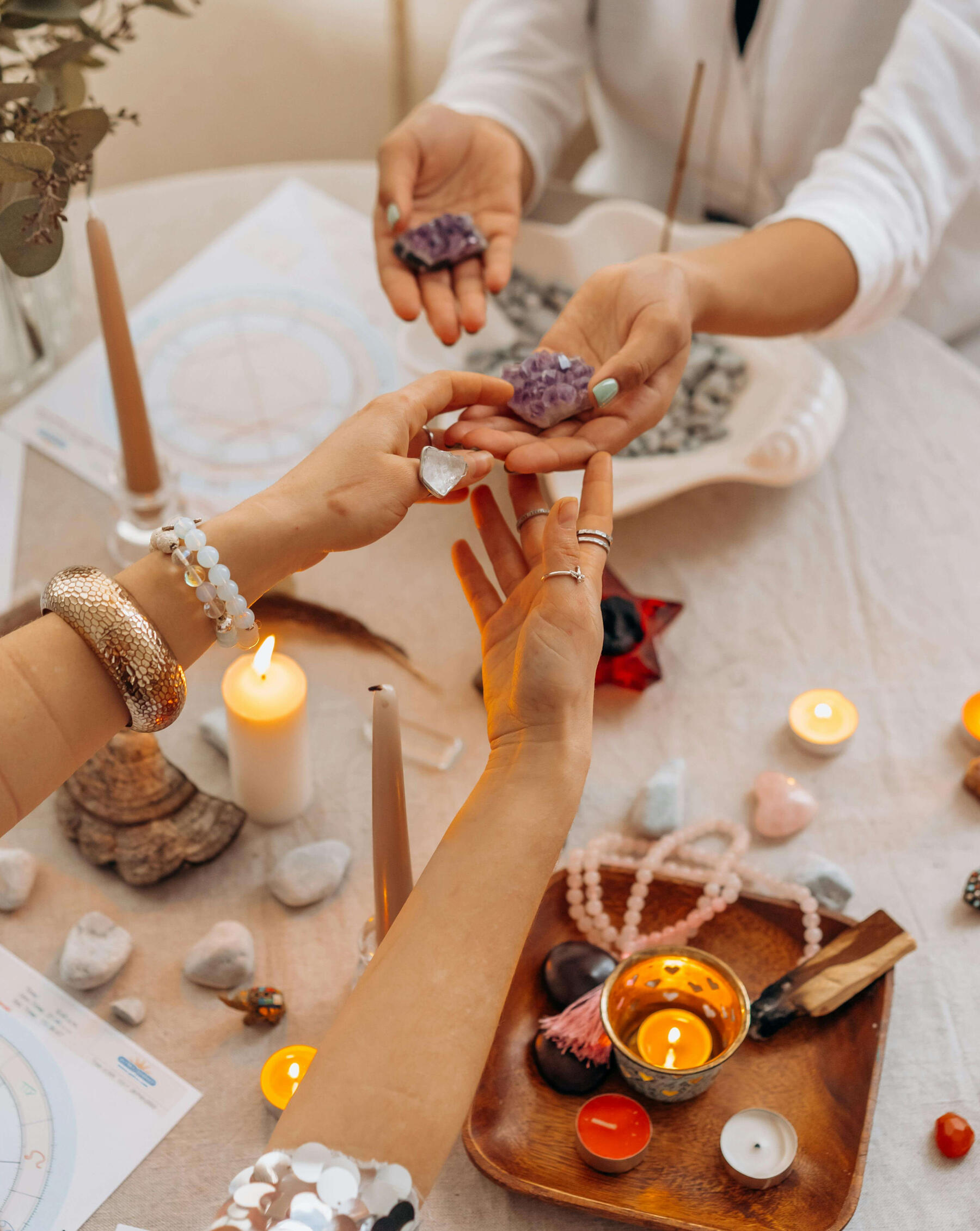 Crystal healing practitioner Photo of two women holding crystals at a table with many crystals, cancles and mala beads.
